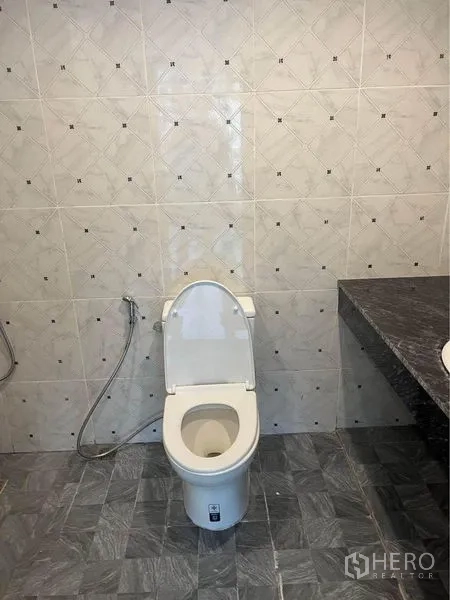 Condominium for rent or sale in Watthana, Bangkok - Tiled bathroom with western toilet, handheld bidet and stone countertop.