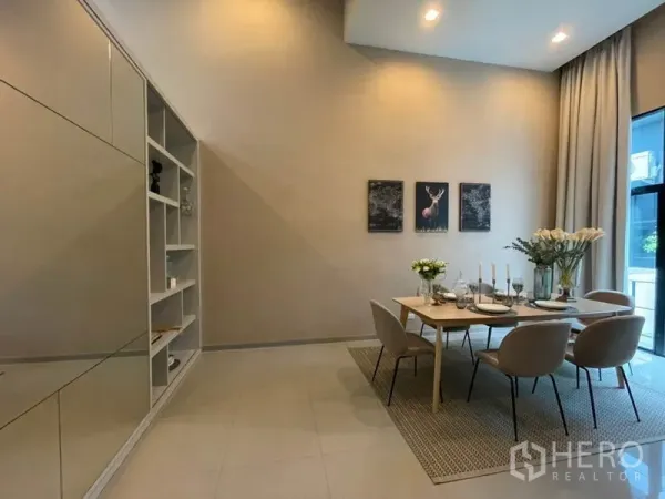 Townhouse for rent or sale in Suan Luang, Bangkok - Bright dining room with floor-to-ceiling curtains, built-in shelving and a mirrored wall.