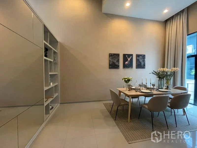 Townhouse for rent or sale in Suan Luang, Bangkok - Bright dining room with floor-to-ceiling curtains, built-in shelving and a mirrored wall.