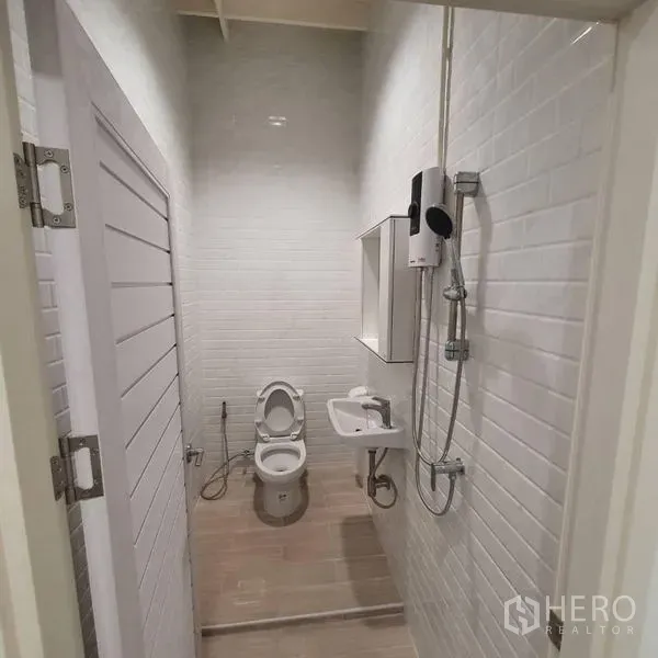 Shophouse for rent or sale in Khlong Toei, Bangkok - Bright tiled bathroom with shower, water heater, sink and toilet.