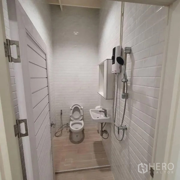 Shophouse for rent or sale in Khlong Toei, Bangkok - Bright tiled bathroom with shower, water heater, sink and toilet.