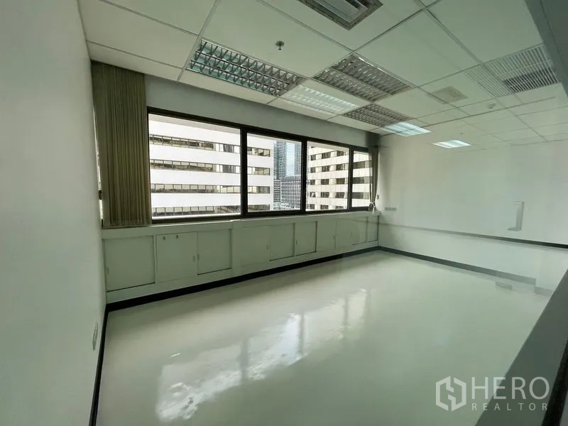 办公空间 出租在Bang Rak, Bangkok - 带窗下矮柜的私密办公室，可见邻近高楼景观