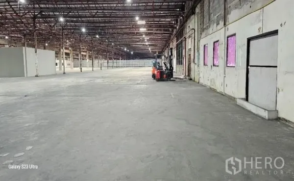 Warehouse for rent in Lam Luk Ka, Pathum Thani - Expansive warehouse interior with high ceiling, steel columns, bright lighting and polished concrete floor.