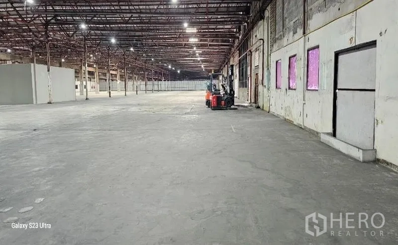 Warehouse for rent in Lam Luk Ka, Pathum Thani - Expansive warehouse interior with high ceiling, steel columns, bright lighting and polished concrete floor.