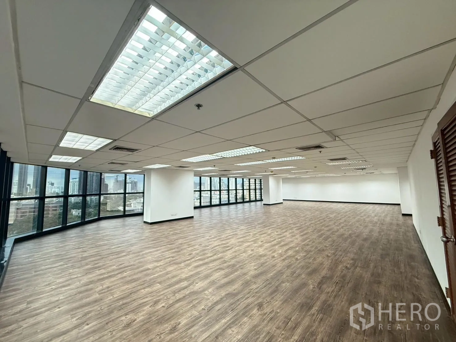 办公室 for rent in Watthana, Bangkok - 转角办公区，环幕玻璃窗与荧光灯顶。