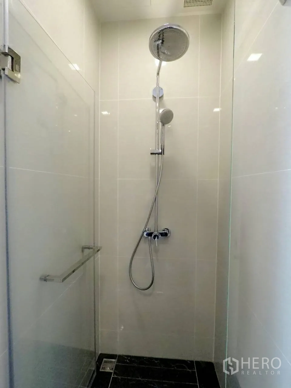 Condominium for rent or sale in Khlong Toei, Bangkok - Modern bathroom with a glass-enclosed rain shower and handheld shower on light tiles.