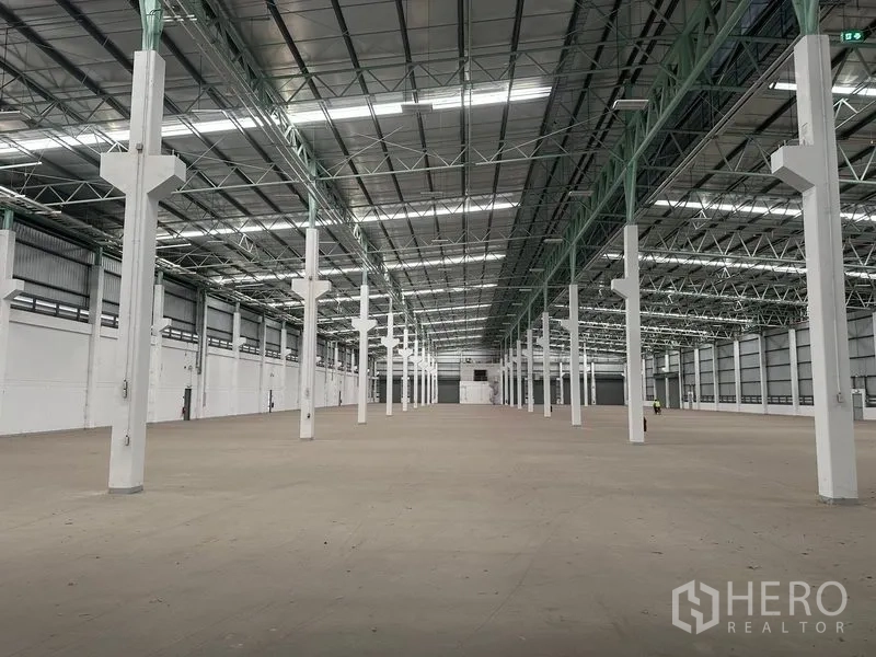 Factory for rent in Bang Sao Thong, Samut Prakan - Open-plan warehouse interior with long bays, steel beams, and visible fire safety points.