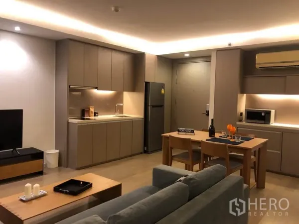 公寓 出租在Watthana, Bangkok - 现代一体化厨房，内置橱柜、餐桌、沙发与电视，开放式布局。
