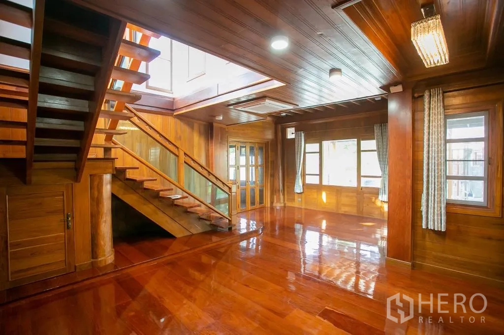 独栋房屋 for rent or sale in Huai Khwang, Bangkok - 大尺度开放式起居区，亮面木地板、窗户与楼梯。