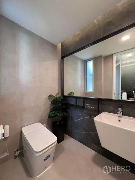 Detached House for sale in Samut Prakan - Contemporary bathroom with a large mirror, wall-mounted sink, and side window.