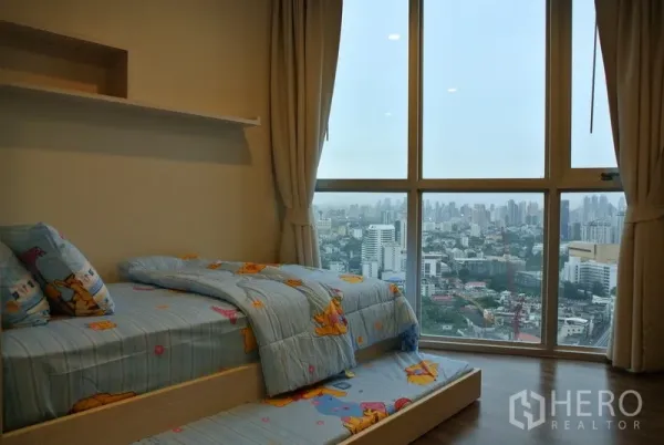 คอนโด ให้เช่าหรือขายในWatthana, Bangkok - ห้องนอนที่สองอบอุ่น เตียงเดี่ยวพร้อมเตียงลิ้นชัก ผ้าม่านโทนสุภาพ พื้นไม้ และหน้าต่างกระจกสูงชมวิวเมืองกว้าง