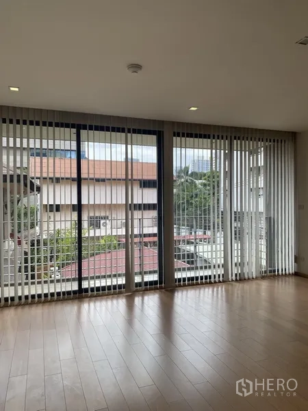 公寓 出租在Pathum Wan, Bangkok - 客厅铺木地板，落地窗与百叶帘，俯瞰巴吞旺社区景观的公寓视野