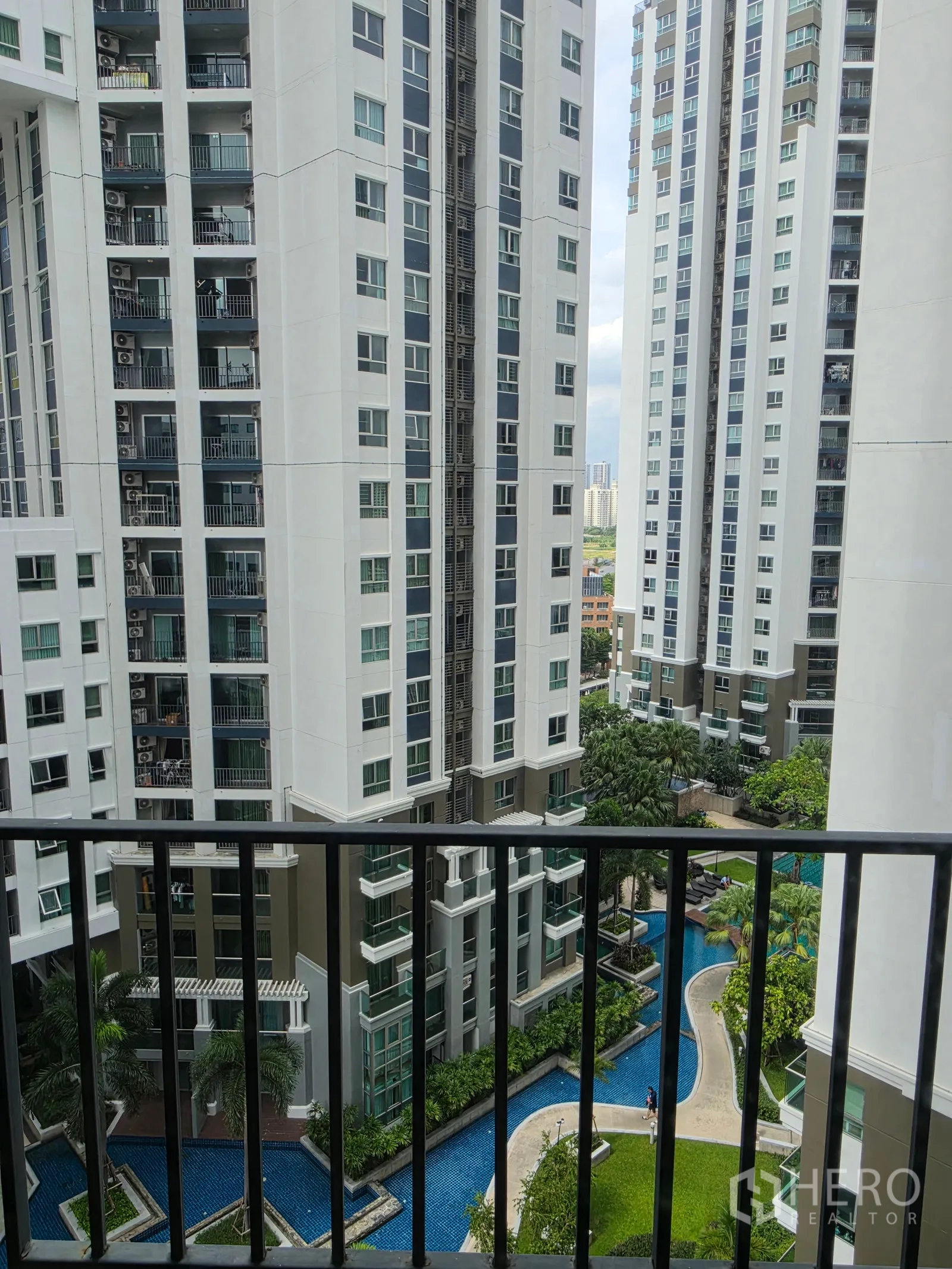 Condominium for rent in Huai Khwang, Bangkok - Balcony view over high-rise towers with landscaped pool and garden below.