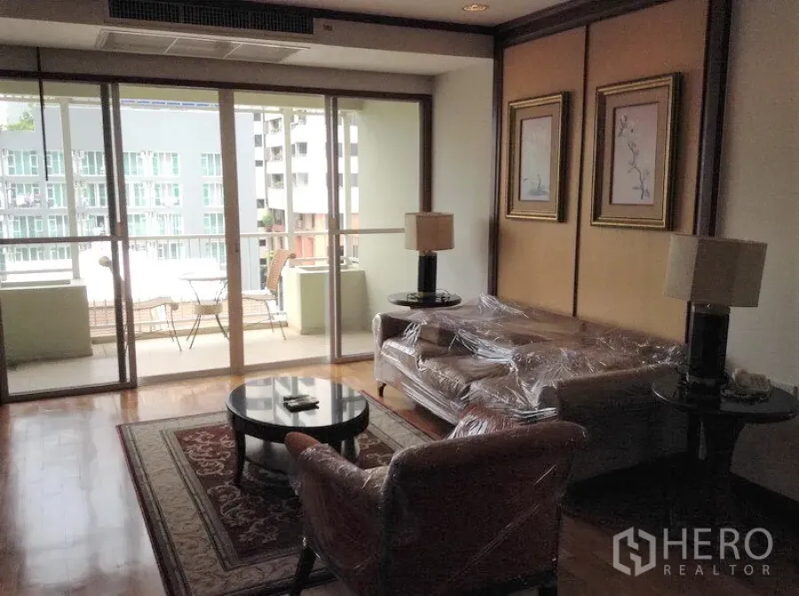 公寓 出租或出售在Watthana, Bangkok - 客厅铺木地板，通向带户外家具的阳台，可览城市景观的公寓。