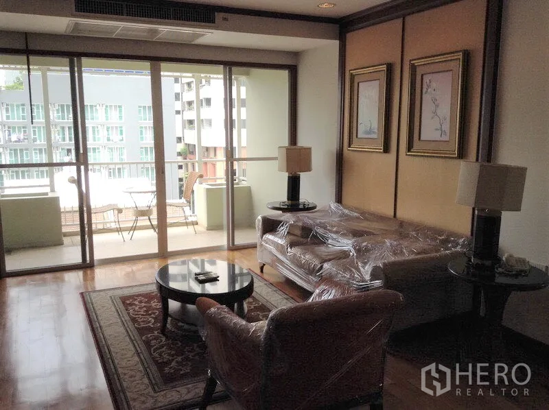 公寓 出租或出售在Watthana, Bangkok - 客厅铺木地板，通向带户外家具的阳台，可览城市景观的公寓。