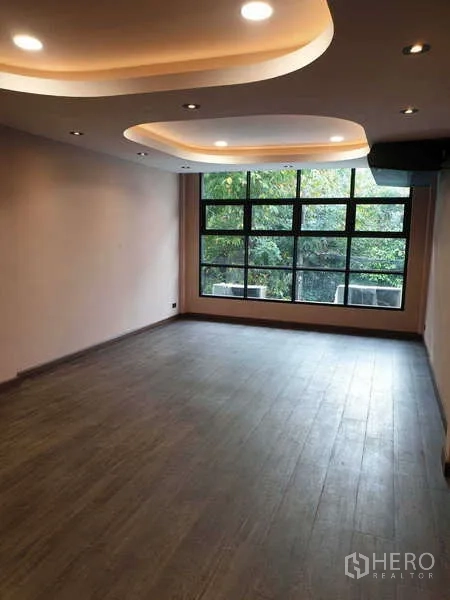 Home Office for rent in Khlong Toei, Bangkok - Large open-plan room with recessed ceiling lights and wide window with greenery view.