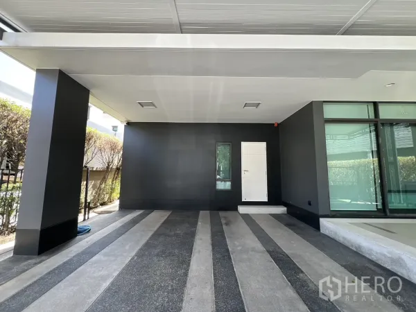Detached House for sale in Bang Kapi, Bangkok - Covered two-car carport with dark feature wall and entry door.