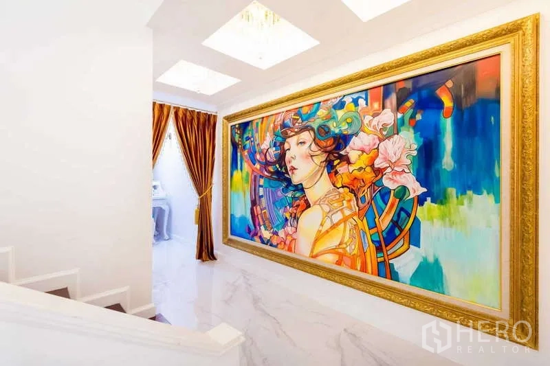 Townhouse for rent in Lat Phrao, Bangkok - Hallway featuring a large colorful framed artwork along white marble walls and skylights.