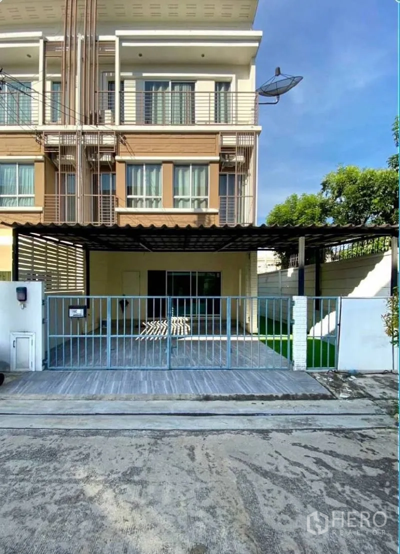 ทาวน์เฮาส์ for rent in Suan Luang, Bangkok - ด้านหน้าทาวน์เฮ้าส์สามชั้นพร้อมระเบียง กระจกบานเลื่อน และที่จอดรถมีหลังคา