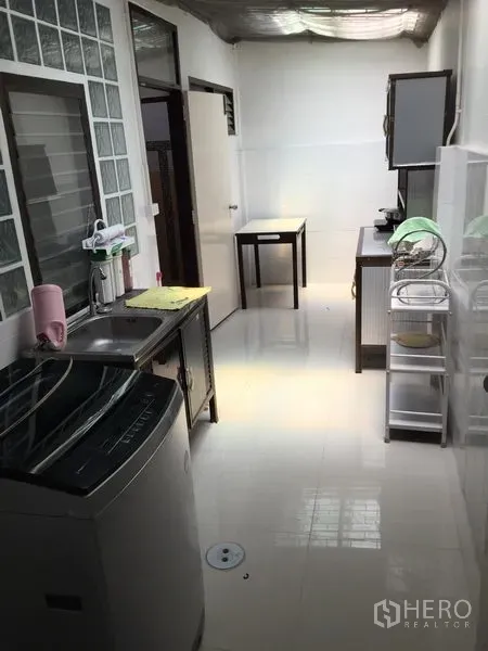 联排别墅 出租在Phra Khanong, Bangkok - 采光良好的长廊式厨房，带水槽、洗衣机与玻璃砖窗。