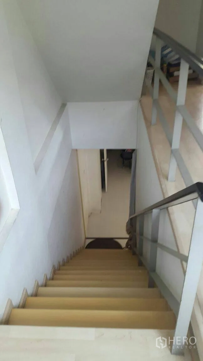 Townhouse for rent in Suan Luang, Bangkok - Light-wood staircase with metal handrail connecting upper and lower floors.