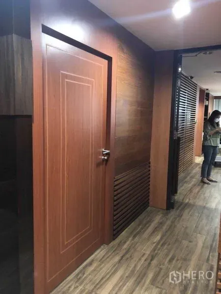Office Space for sale in Watthana, Bangkok - Office corridor with wooden door, panel accents, and downlights.
