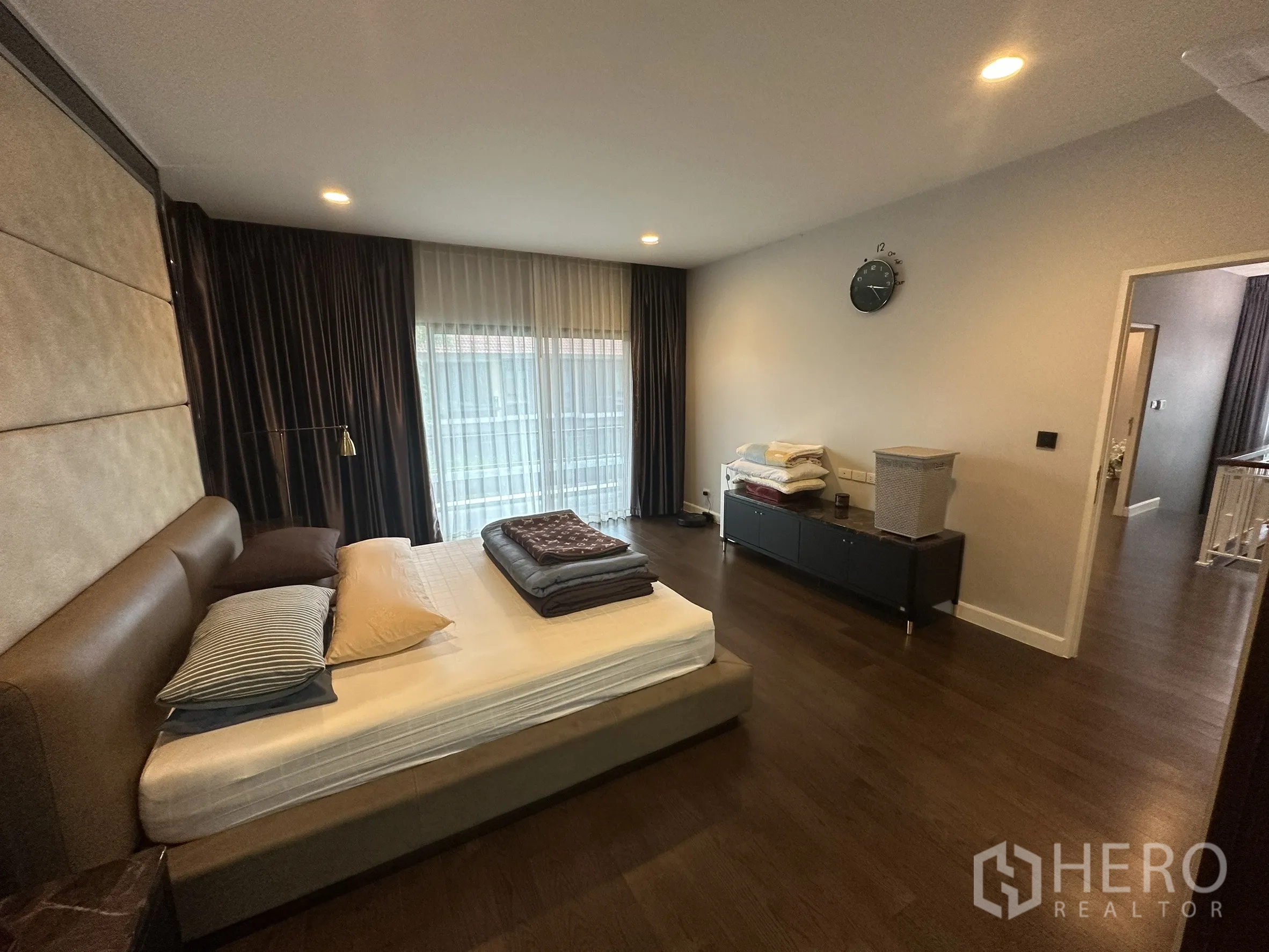 Detached House for rent in Lam Luk Ka, Pathum Thani - Spacious master bedroom with padded headboard and floor-to-ceiling curtains.