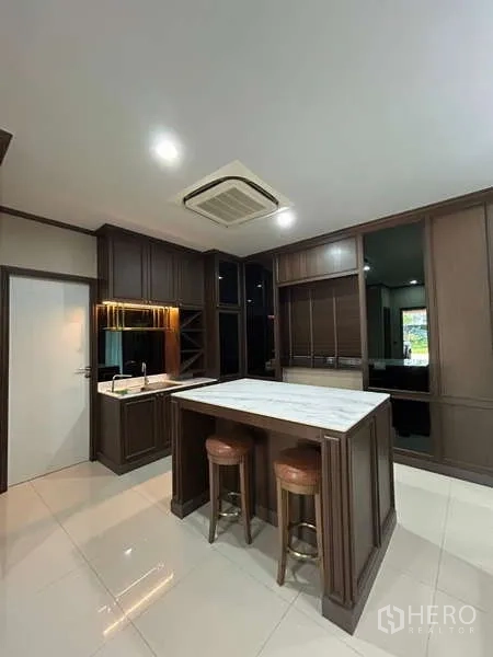 Detached House for rent in Bang Kapi, Bangkok - Western kitchen with marble island, dark wood cabinetry, and ceiling cassette AC.