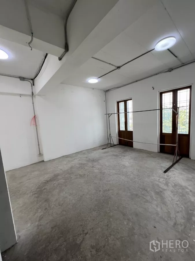 Retail Space for rent in Khlong Toei, Bangkok - Large white studio room with two balcony doors and ceiling lights.