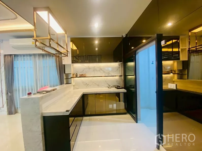 独立式住宅 出租在Prawet, Bangkok - 主厨房配大理石台面与L形橱柜，设滑动玻璃门。
