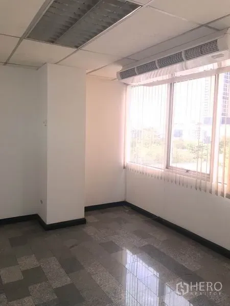 Office Space for rent in Khlong Toei, Bangkok - Bright corner office with large windows, vertical blinds, built-in air conditioning and stone-pattern tile floors.