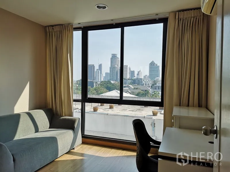 公寓 出售在Watthana, Bangkok - 次卧/书房，沙发与书桌，大窗外是城市景观