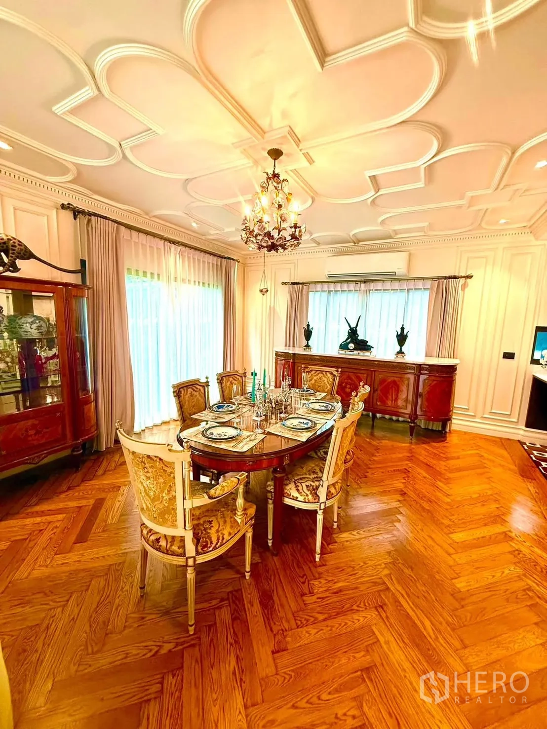 Detached House for rent in Bang Kapi, Bangkok - Elegant dining room with round table, chandelier, and herringbone floor.