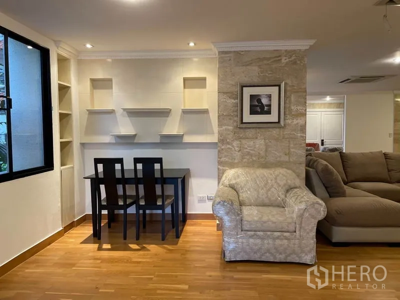 Condominium for rent in Watthana, Bangkok - Study nook with built-in display shelves, desk and an armchair beside a bright window.