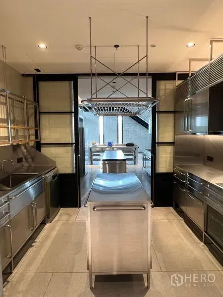 Condominium for rent in Sathon, Bangkok - Professional-grade stainless-steel kitchen with a central island and hanging rack.
