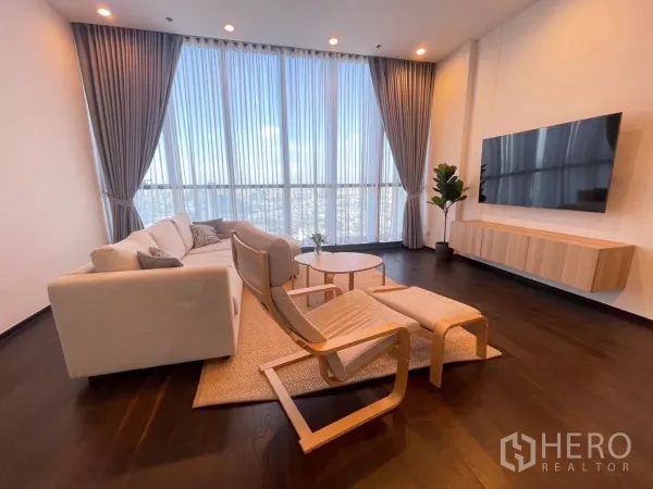 公寓 出租在Phra Khanong, Bangkok - 客厅采光充足，落地窗与城市天际线景观，配沙发与壁挂电视。