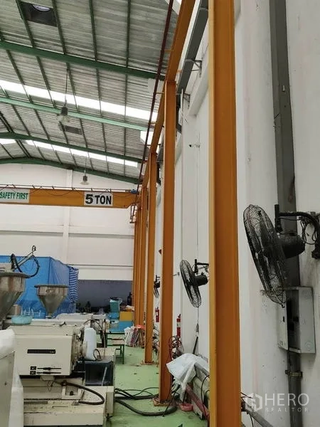 Factory for sale in Sai Noi, Nonthaburi - Side view of production line with wall-mounted fans and crane beam.