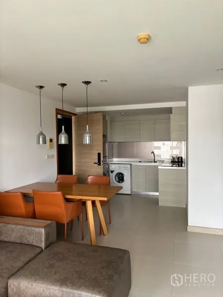公寓 出租在Watthana, Bangkok - 客餐厅一体，望向紧凑厨房，设吊灯与洗衣机。