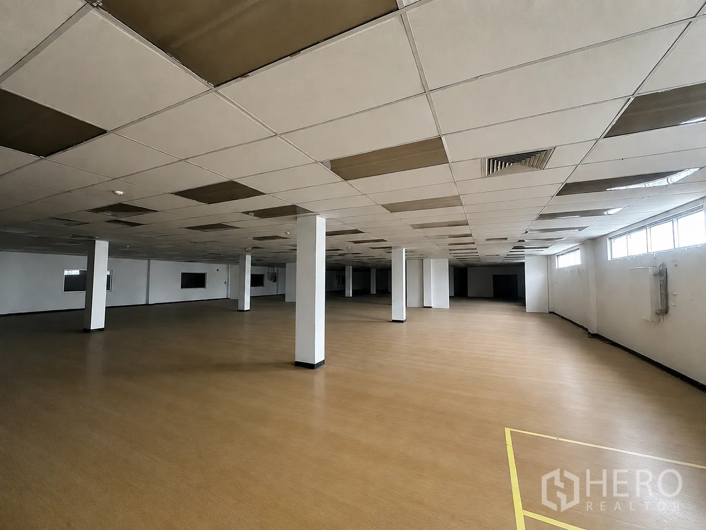 Factory for rent or sale in Wang Noi, Phra Nakhon Si Ayutthaya - Another angle of the brown-floor hall showing windows, ceiling vents, and structural columns.