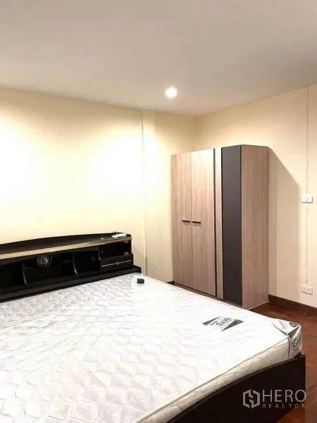 Townhouse for rent in Bang Na, Bangkok - Second bedroom with bedframe, freestanding wardrobe and warm downlights.