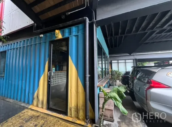 零售空间 出租 - 蓝色集装箱商铺外立面，玻璃门，旁边为有顶停车位，靠近Ekkamai。