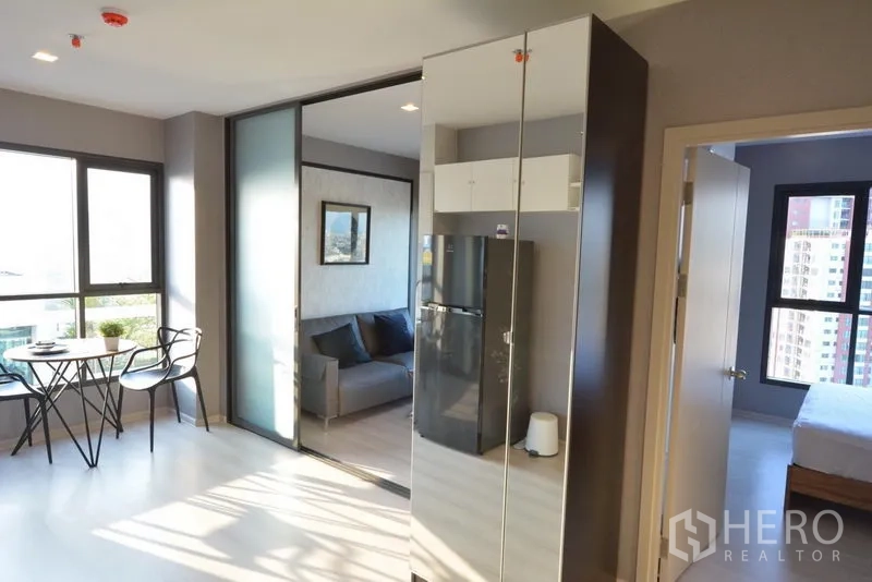Condominium for sale in Khlong Toei, Bangkok - Sunlit 1-bedroom condo with window dining set, sliding glass partition, and access to the bedroom.