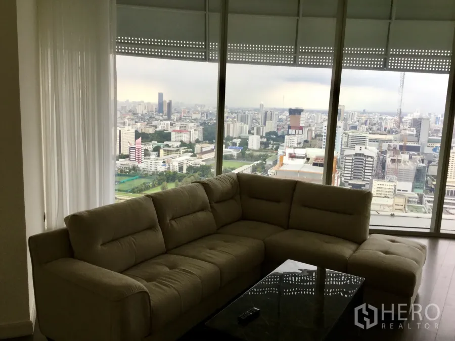 公寓 出租在Pathum Wan, Bangkok - 客厅采光充足，设大转角沙发与落地窗，可眺望曼谷天际线与高尔夫草坪。