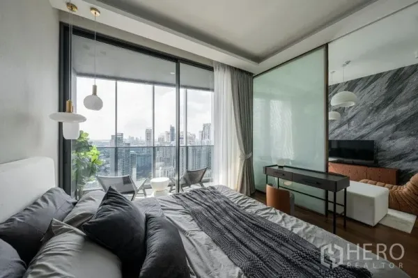 Condominium for rent in Khlong Toei, Bangkok - Bedroom with desk and sliding glass to the balcony, offering sweeping city views from a Khlong Toei condo.