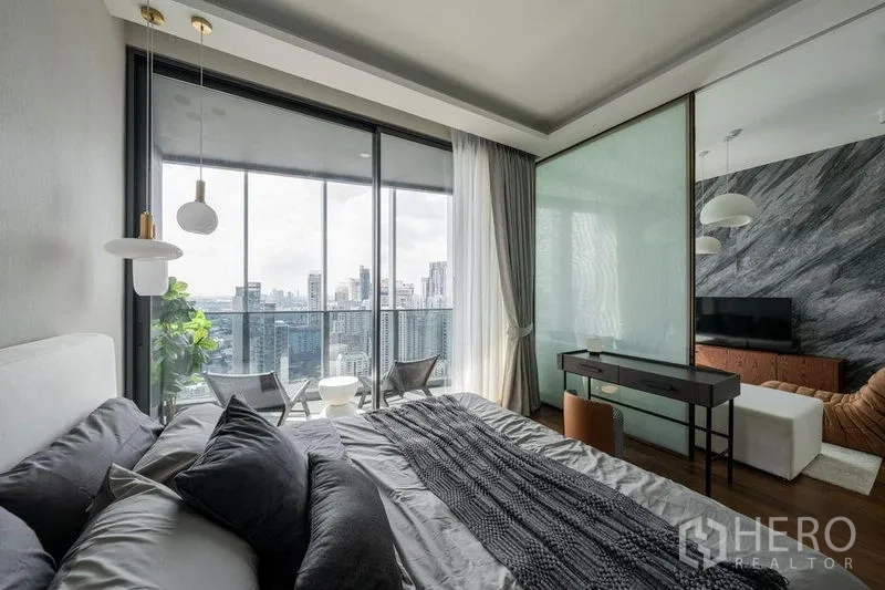 Condominium for rent in Khlong Toei, Bangkok - Bedroom with desk and sliding glass to the balcony, offering sweeping city views from a Khlong Toei condo.