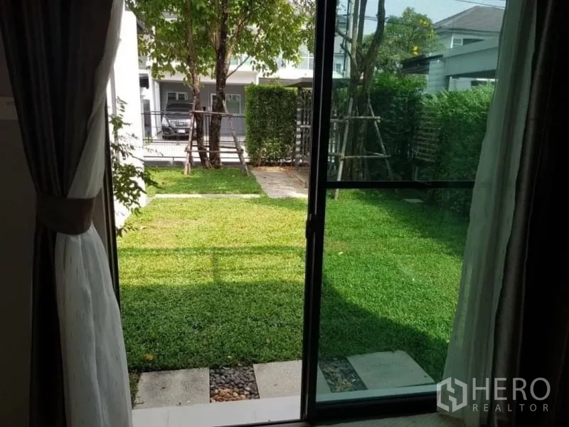 Detached House for rent in Bang Phli, Samut Prakan - Sliding door opening to a green lawn and hedge-lined backyard.