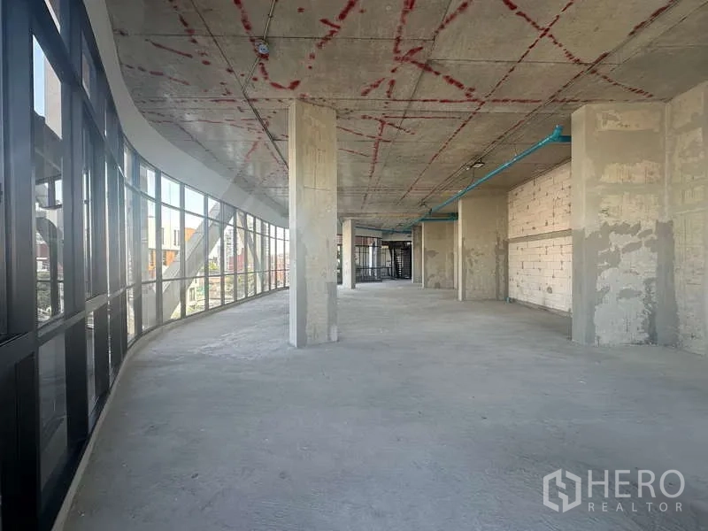 Retail Space for rent in Phra Khanong, Bangkok - Long open retail hall with full-height glass facade on the left, structural columns, and bare concrete floor.