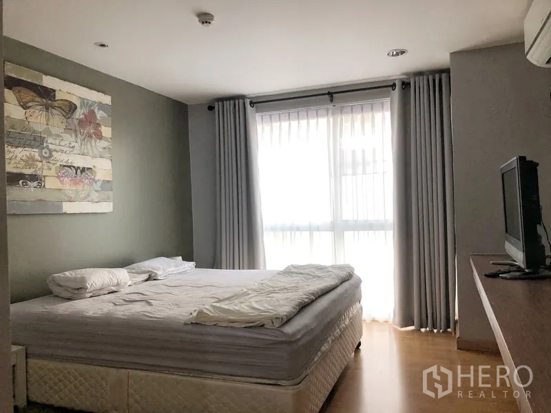 Condominium for rent or sale in Khlong Toei, Bangkok - Master bedroom with large window, blackout curtains and a king-size bed.