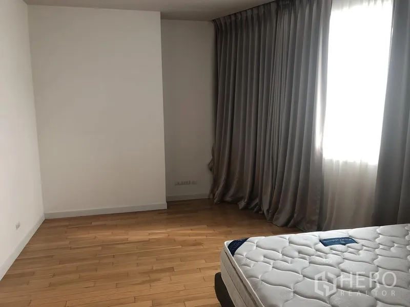 Condominium for rent in Khlong Toei, Bangkok - Master bedroom corner with wide windows, blackout curtains and ample floor space.
