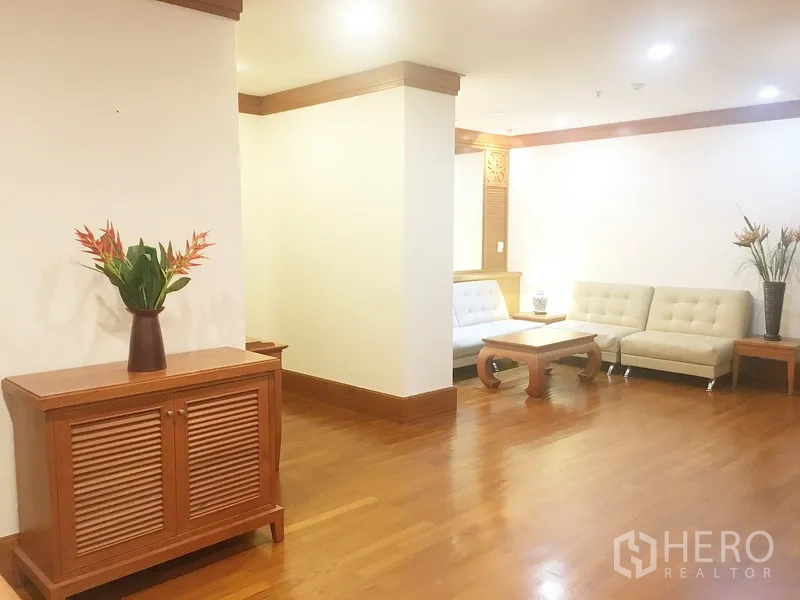 公寓 出租在Pathum Wan, Bangkok - 开放式客厅，实木地板、边柜与转角沙发区。